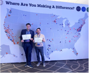 Cody, right, poses with another Violence Fellow, Jay Franzone, in front of a map showing where each Fellow is making a difference.