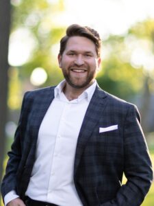 Kameron Nelson, new CEO of Lost&Found. A smiling thirty-something man with a beard, wearing a suit jacket, white shirt, no tie.