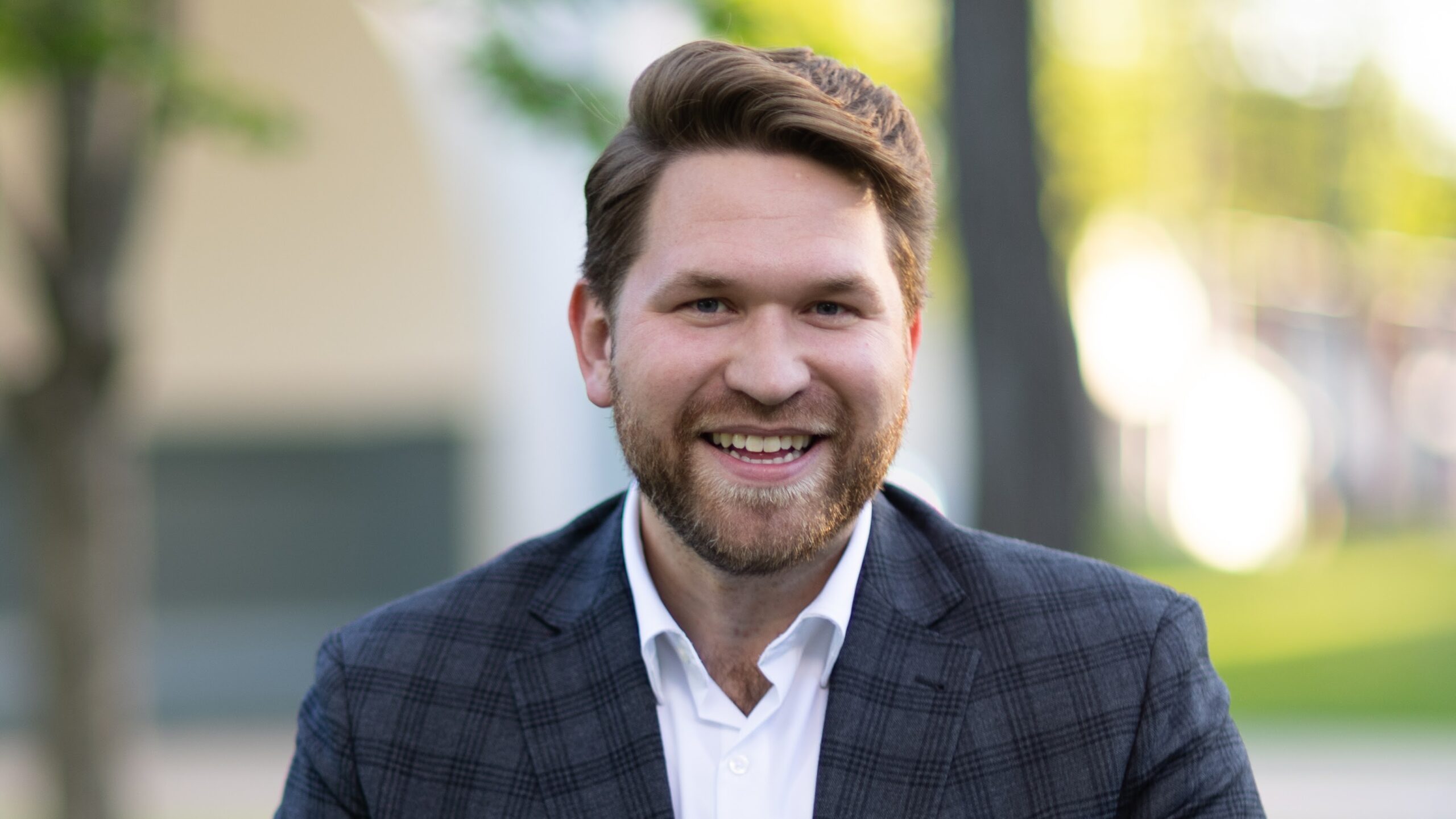 Kameron Nelson, new CEO of Lost&Found. A smiling thirty-something man with a beard, wearing a suit jacket, white shirt, no tie.