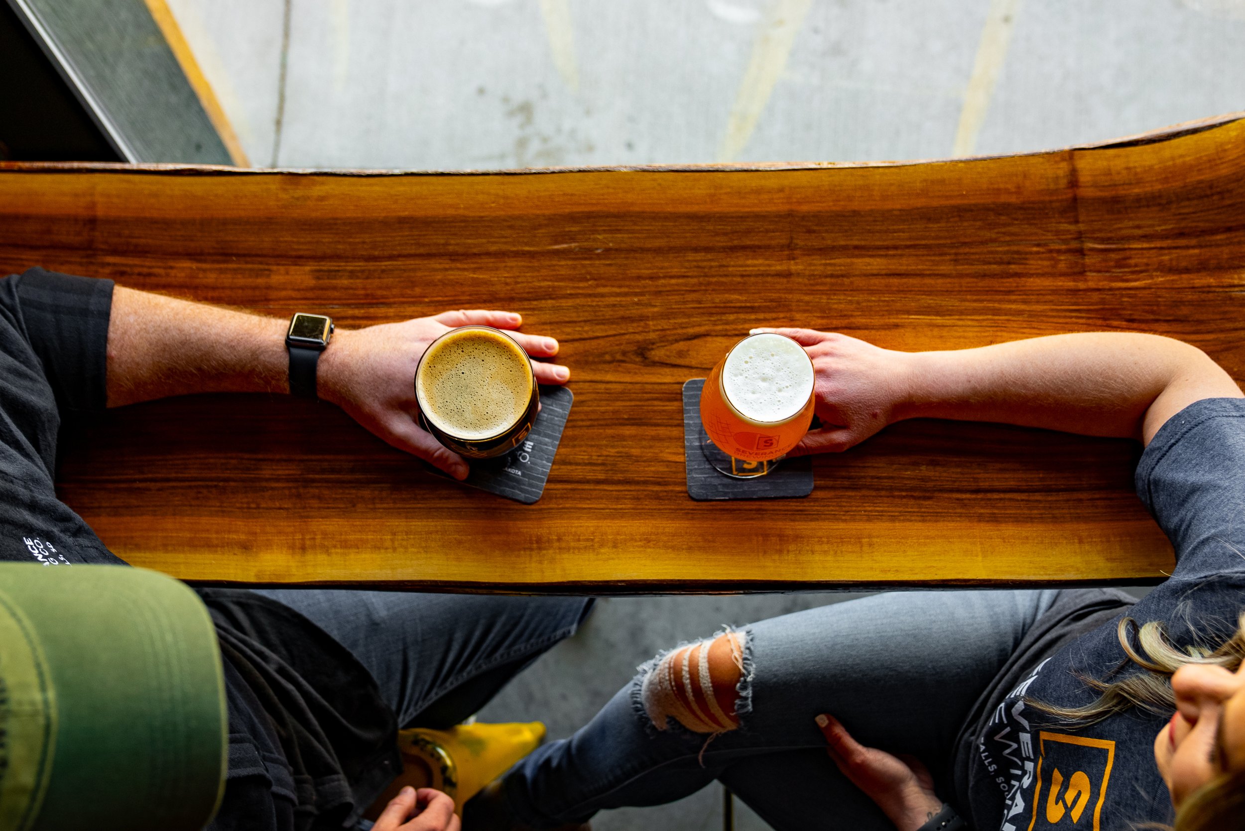 Aerial photo of a man and woman sitting at a bar holding beer glasses.