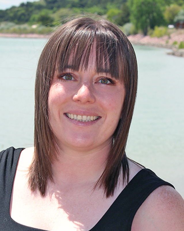 Whitney Bischoff smiles in front of an outdoor water scene.